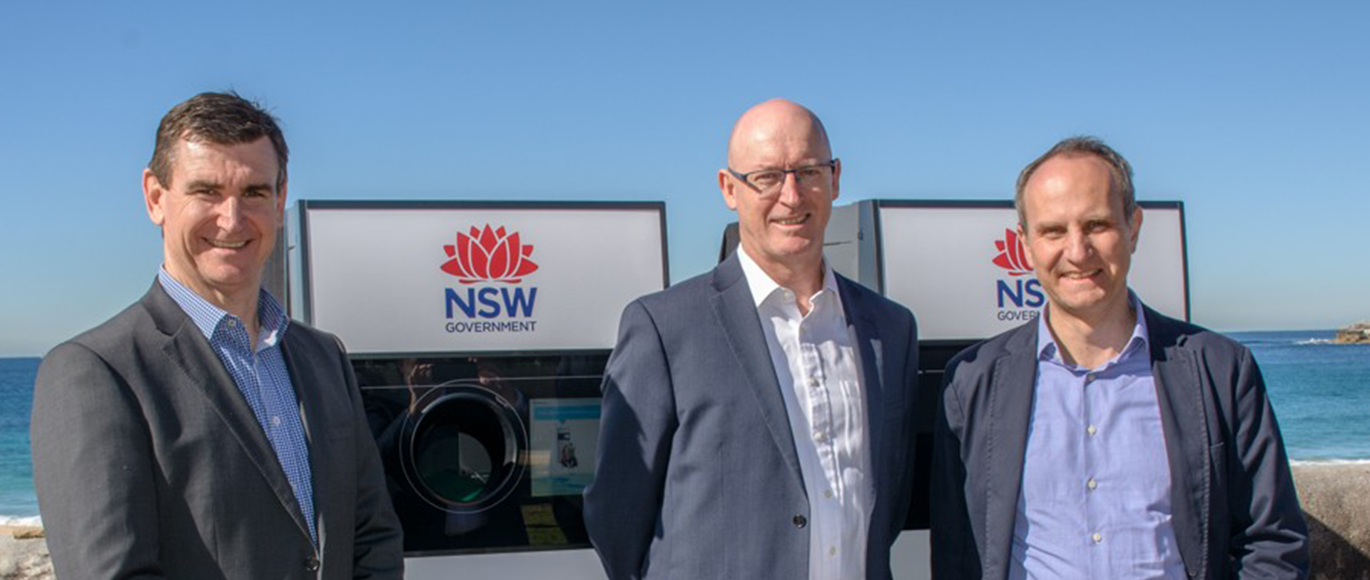 Drei Männer im Anzug vor New South Wales Leergutrücknahme-Automaten